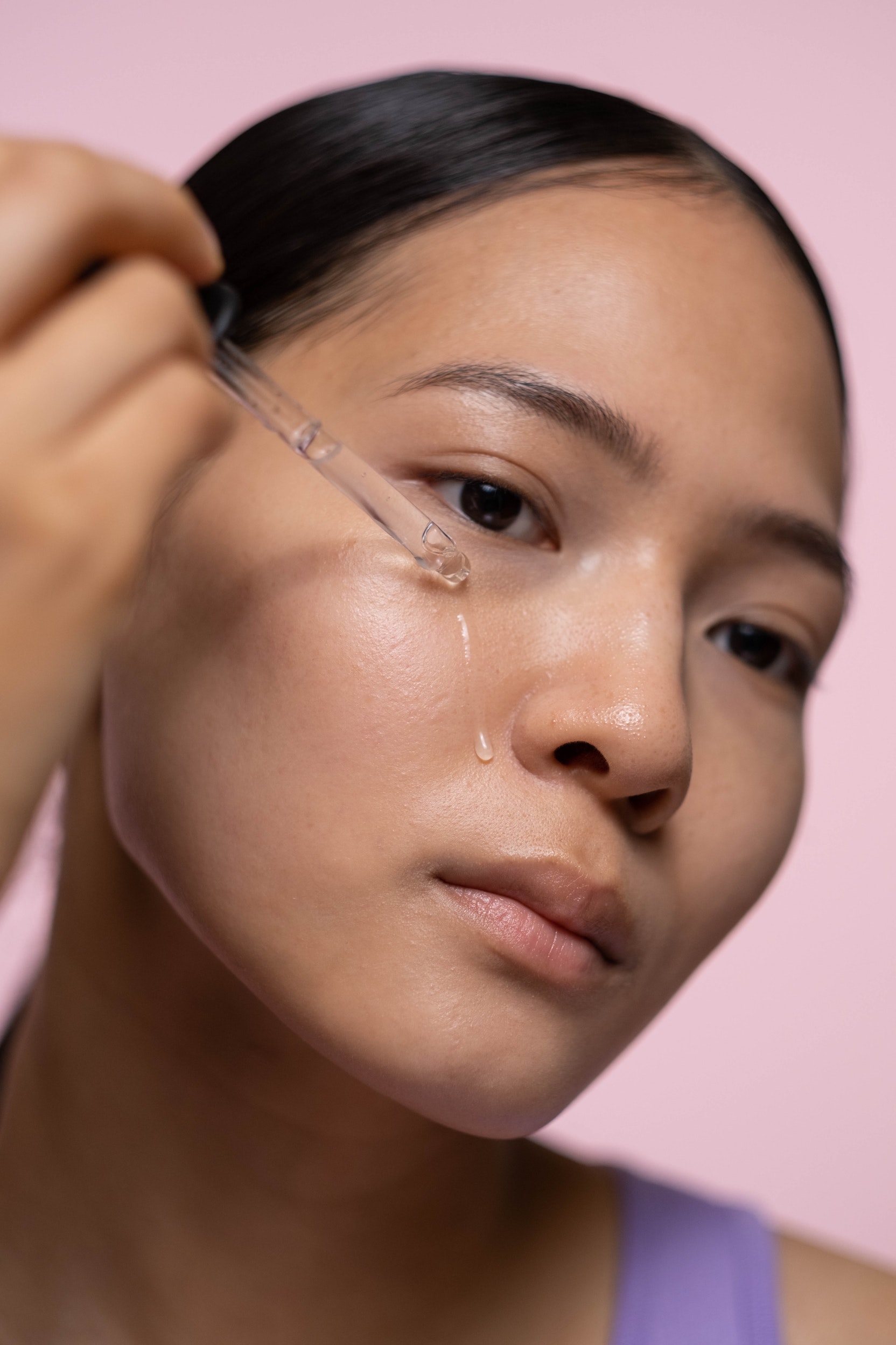 Woman applying a drop of oil onto her face with a pipette