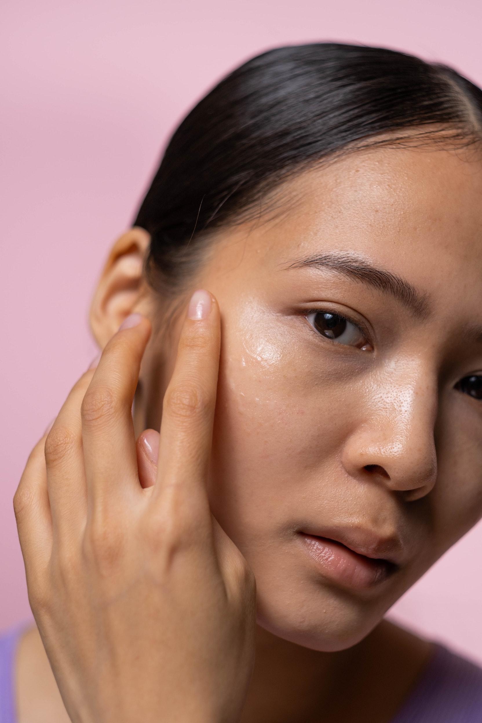 A woman applying a serum to her cheekbone